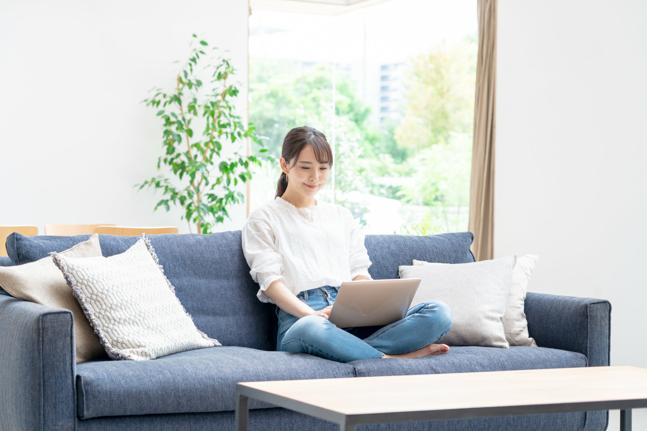 ソファーに座ってオンライン英会話を楽しむ女性の画像